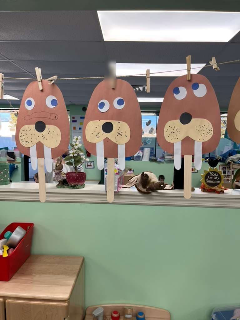 Paper walrus masks made by the children hang from a line across the classroom.